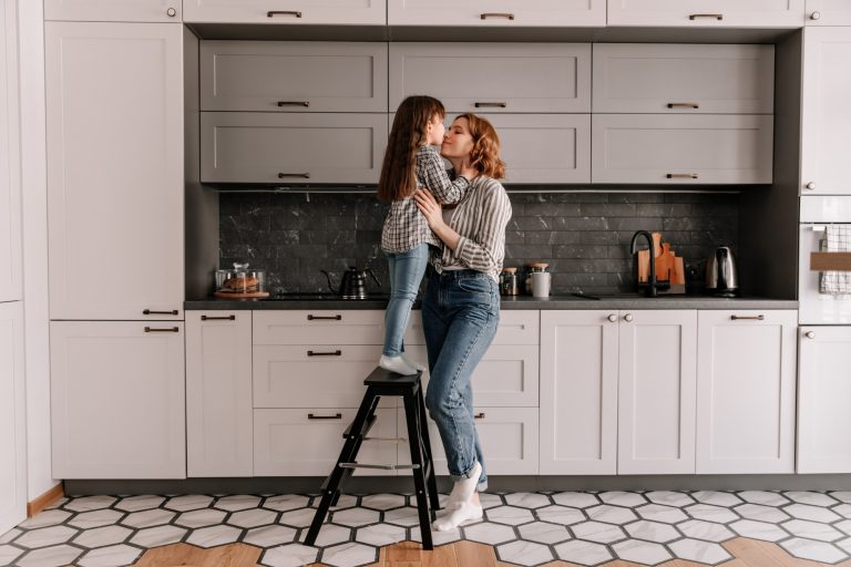 portrait little girl stands stairs hugs mother kitchen